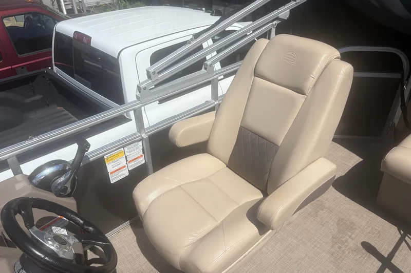 Slide: The Image of 2021 Sun Tracker Party Barge 20 DLX boat interior with beige captain's chair and steering wheel. - 8