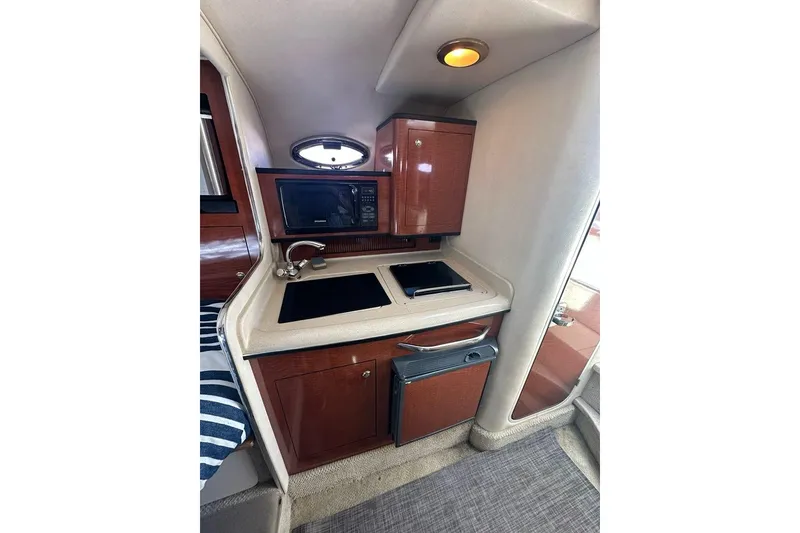 Slide: The Image of 2004 Sea Ray 280 Sundancer cabin kitchen with microwave, sink, and storage cabinets. - 13