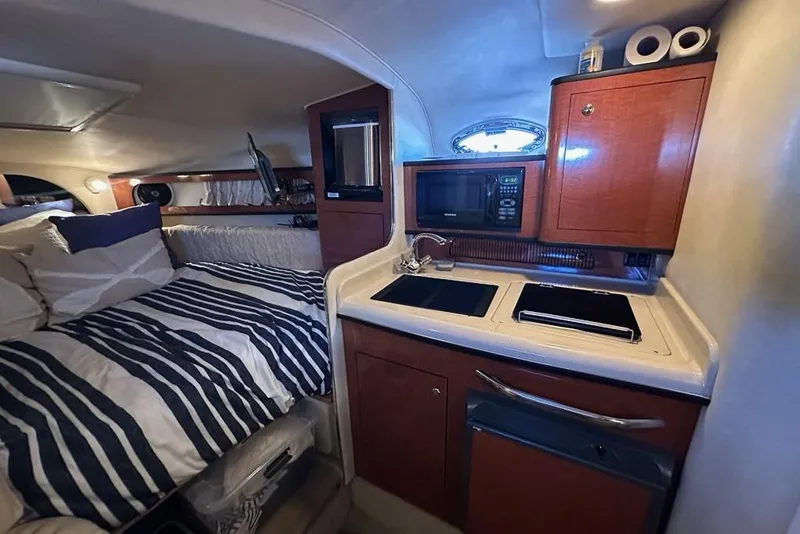 Slide: The Image of 2004 Sea Ray 280 Sundancer cabin with kitchenette and cozy sleeping area. - 14