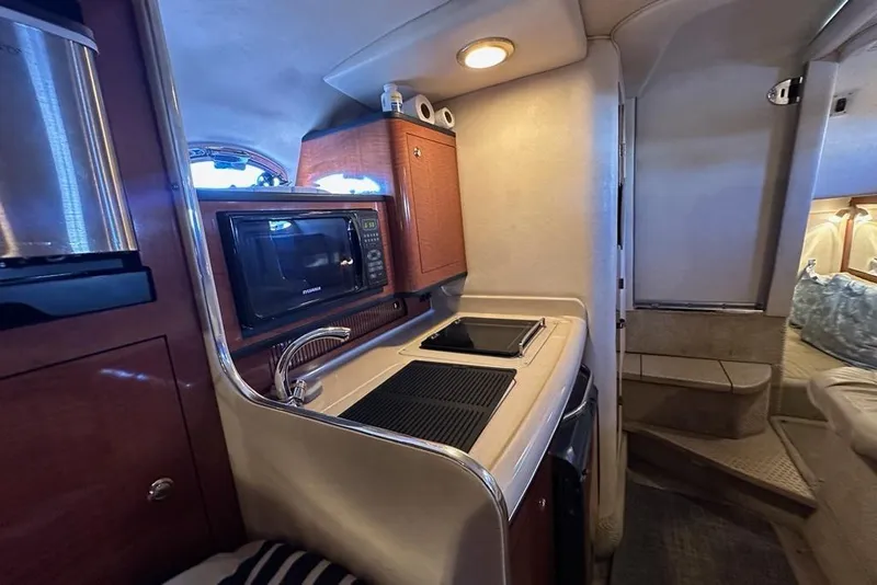Slide: The Image of 2004 Sea Ray 280 Sundancer interior kitchen with microwave, sink, and stove. - 15