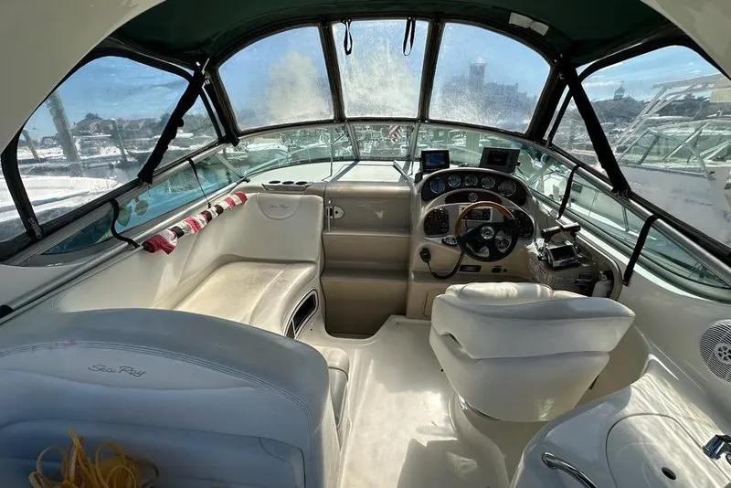 Slide: The Image of 2004 Sea Ray 280 Sundancer cockpit with steering wheel and seating, featuring navigation equipment. - 2