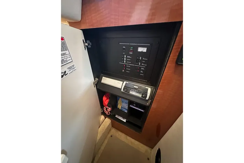Slide: The Image of Electrical panel inside 2004 Sea Ray 280 Sundancer boat, featuring control switches and storage. - 23