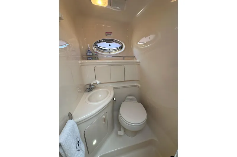 Slide: The Image of 2004 Sea Ray 280 Sundancer bathroom with sink, toilet, and porthole window. - 26