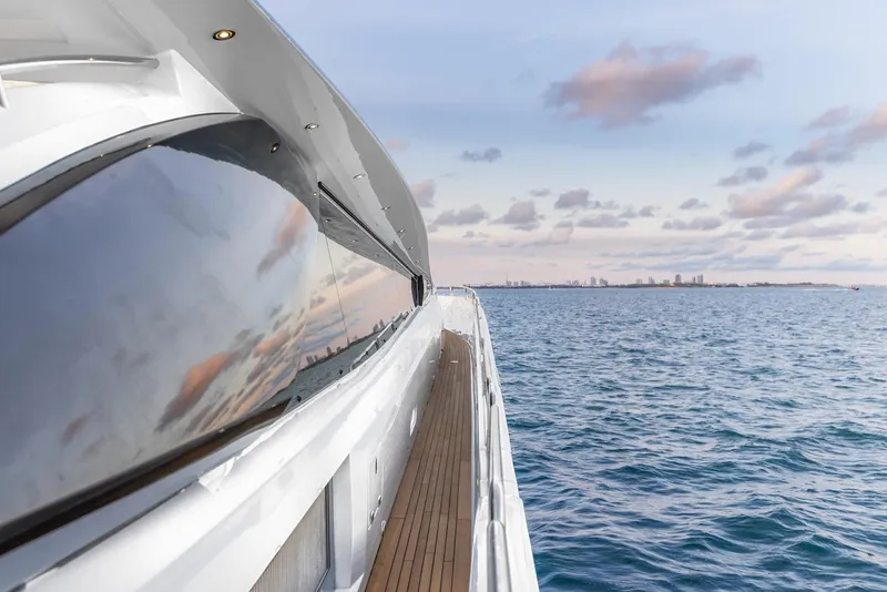 Slide: The Image of 2008 Sunseeker Predator 108 yacht cruising on open sea with city skyline in background. - 40