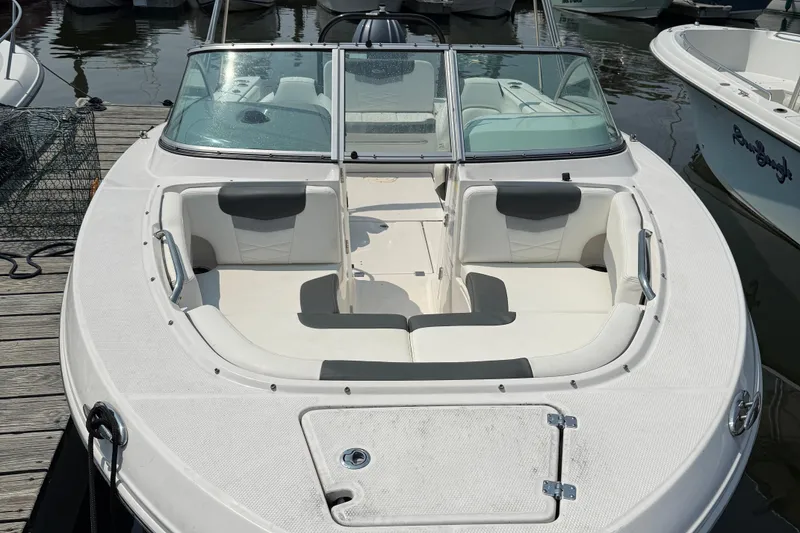 Slide: The Image of 2023 Robalo R207 Dual Console boat with white seating, docked at marina. - 1