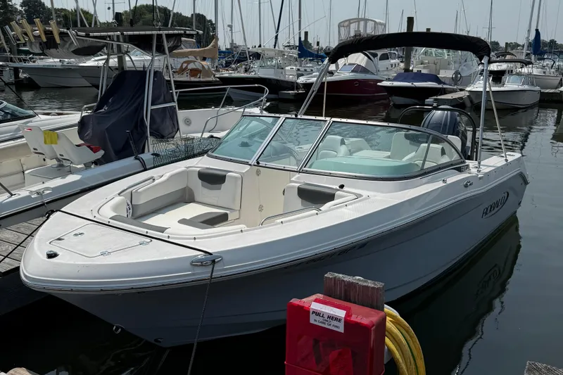 Slide: The Image of 2023 Robalo R207 Dual Console boat docked at marina, surrounded by other vessels. - 2