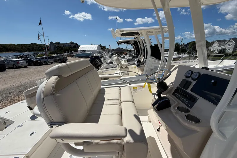 Slide: The Image of 2026 Boston Whaler 250 Dauntless boat interior with helm and seating, docked under blue sky. - 12