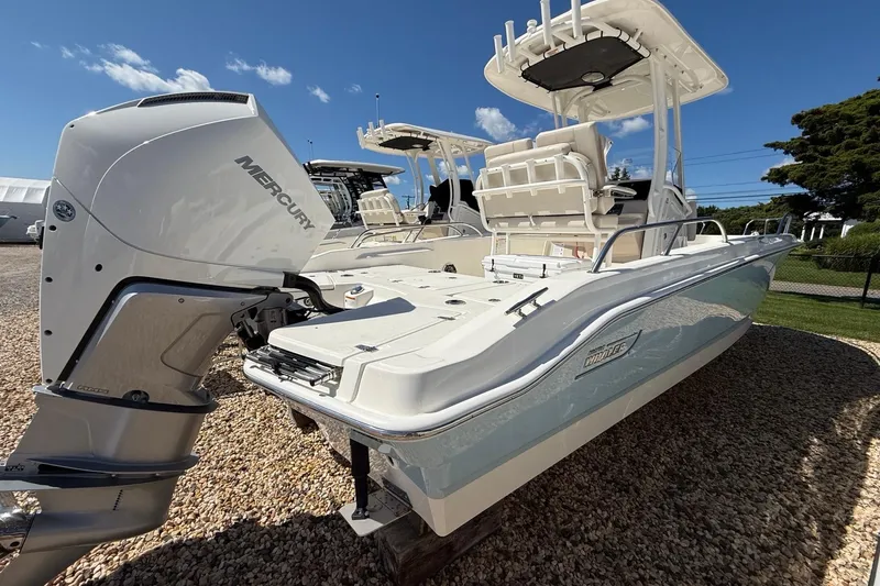 Slide: The Image of 2026 Boston Whaler 250 Dauntless boat with Mercury engine, parked on gravel. - 2
