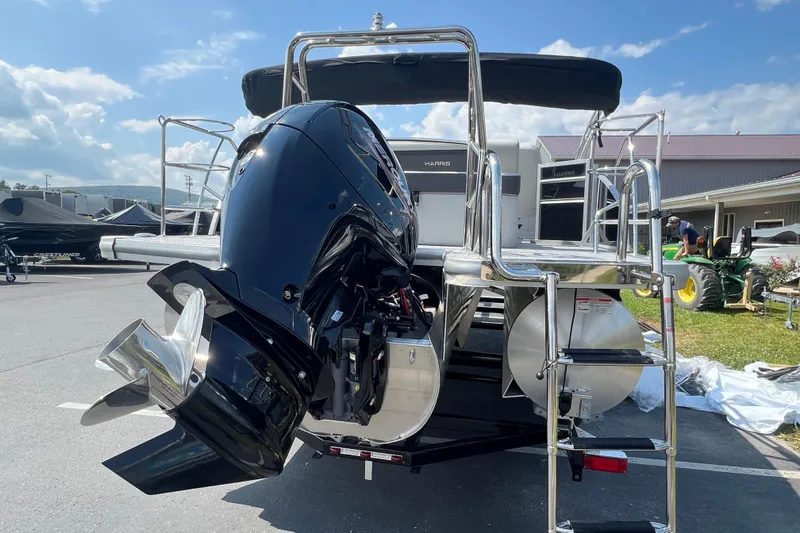 Slide: The Image of 2025 Harris Cruiser 230 pontoon boat with powerful outboard motor, parked outdoors. - 7
