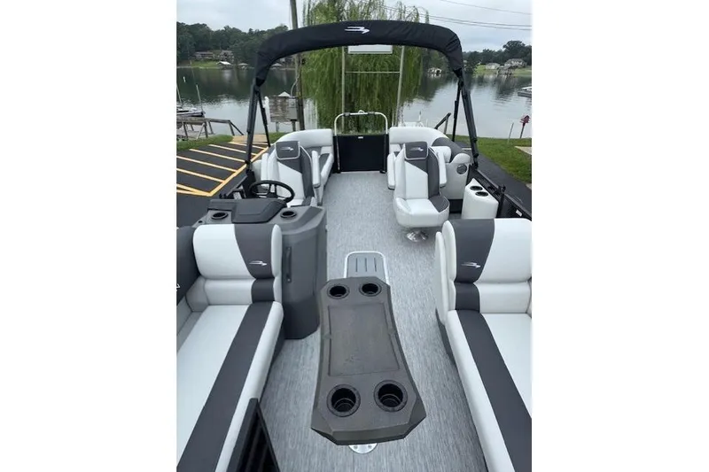Slide: The Image of 2026 Bennington 22 SSR pontoon boat interior with seating and table, docked by a lake. - 3