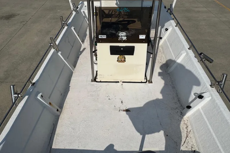 Slide: The Image of 1998 Coastal Skiff 19 boat interior with console, rod holders, and shadow on deck. - 7