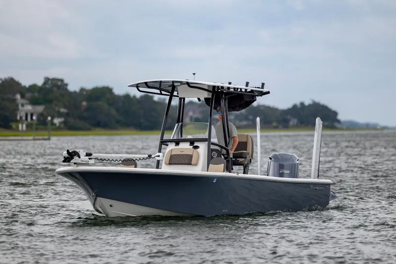 Slide: The Image of 2022 Tidewater 2300 Carolina Bay boat cruising on a calm lake with scenic background. - 2