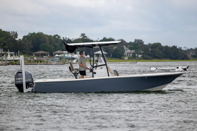 Slide: The Image of 2022 Tidewater 2300 Carolina Bay boat on water, with person steering, Yamaha engine visible. - 7