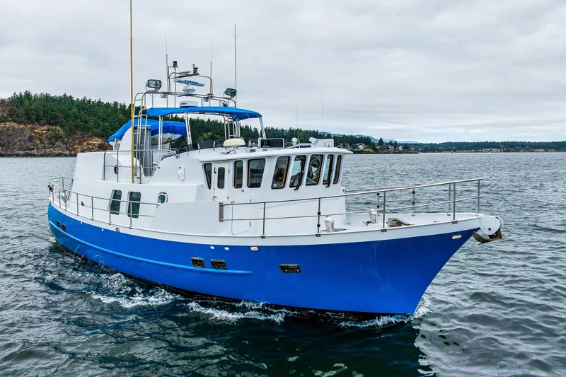 Slide: The Image of 1978 Hidden Harbor Custom Trawler cruising on a scenic waterway with lush green shoreline. - 1