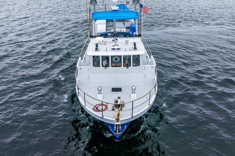 Slide: The Image of 1978 Hidden Harbor Custom Trawler on open water, featuring blue canopy and American flag. - 11