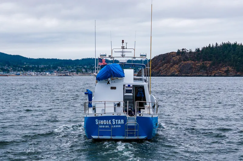 Slide: The Image of 1978 Hidden Harbor Custom Trawler on water, near forested coastline, overcast sky. - 12