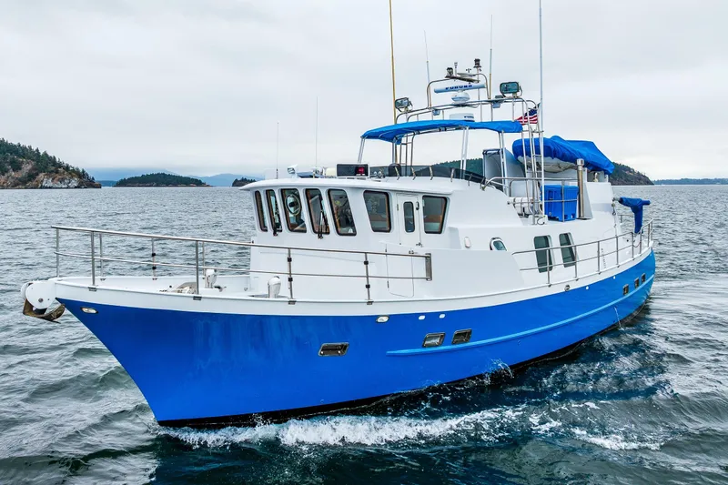 Slide: The Image of 1978 Hidden Harbor Custom Trawler cruising on open water, featuring a blue and white design. - 16
