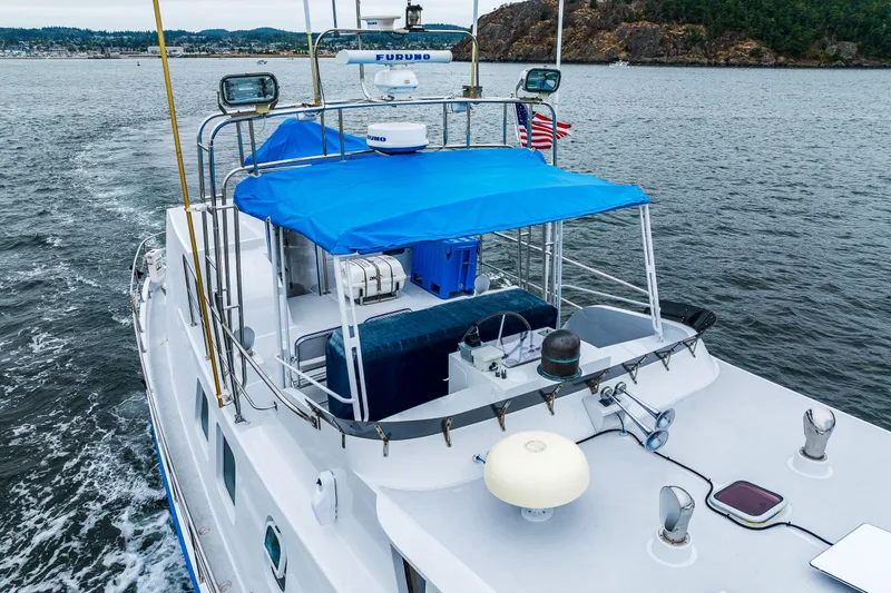 Slide: The Image of 1978 Hidden Harbor Custom Trawler with blue canopy cruising on scenic waters. - 18