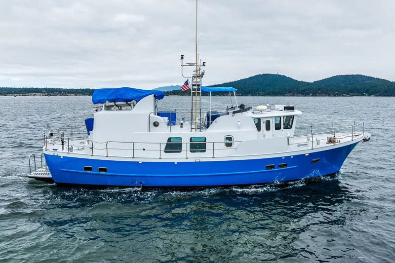 Slide: The Image of 1978 Hidden Harbor Custom Trawler cruising on open water with scenic mountain backdrop. - 20