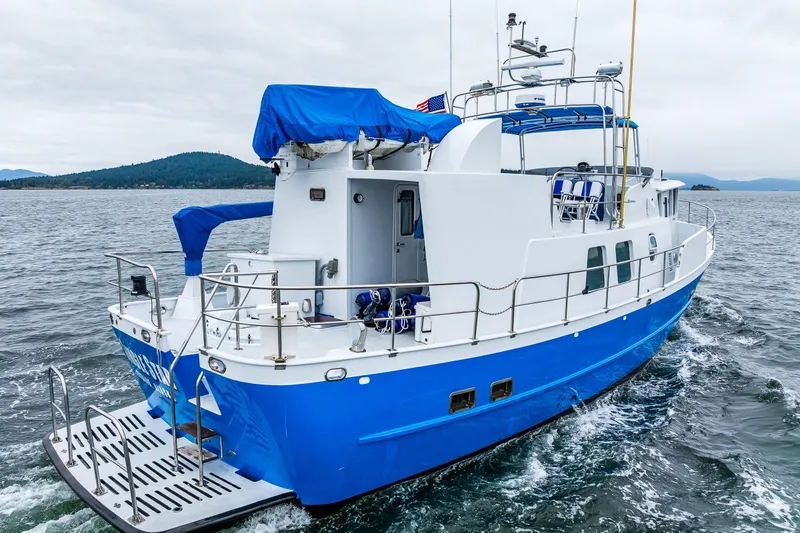 Slide: The Image of 1978 Hidden Harbor Custom Trawler cruising on open water, featuring blue and white design. - 21