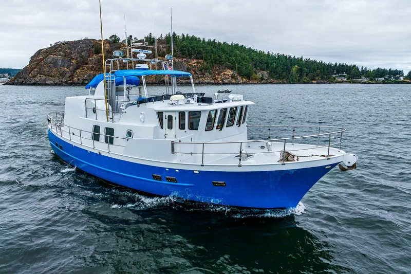 Slide: The Image of 1978 Hidden Harbor Custom Trawler cruising in scenic waters near rocky shoreline. - 3