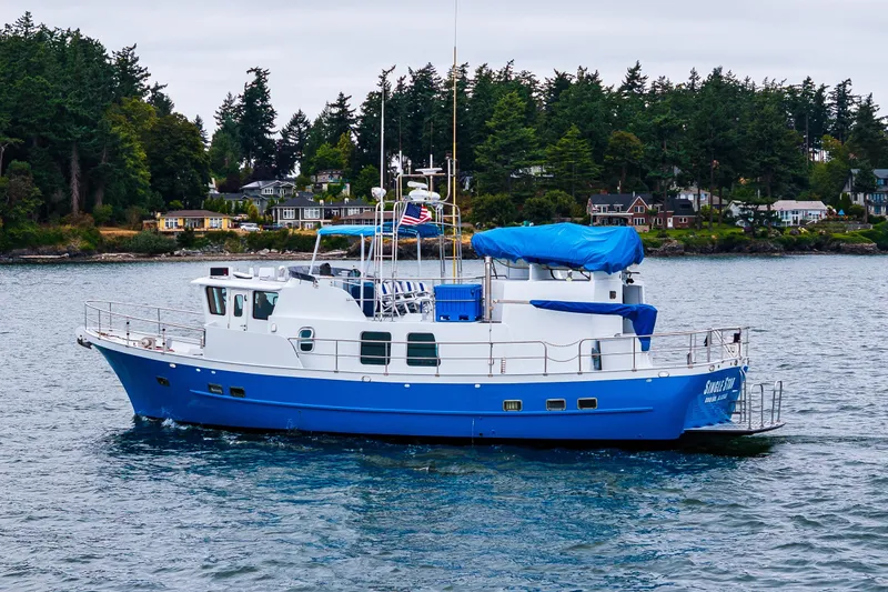 Slide: The Image of 1978 Hidden Harbor Custom Trawler on water, surrounded by lush greenery and coastal homes. - 4