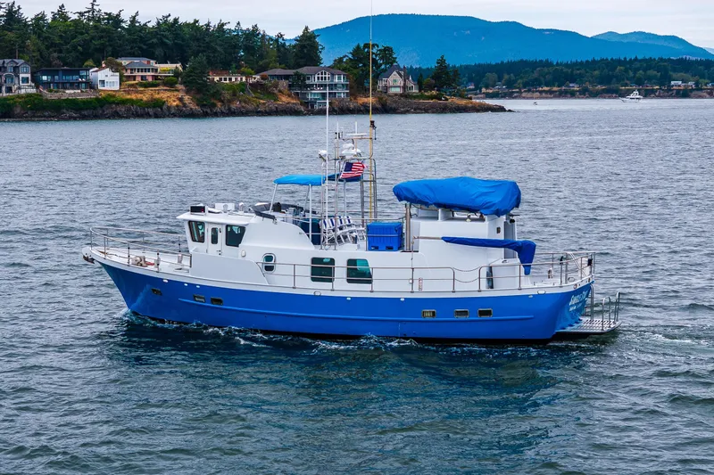 Slide: The Image of 1978 Hidden Harbor Custom Trawler cruising on scenic waters with coastal homes in the background. - 7