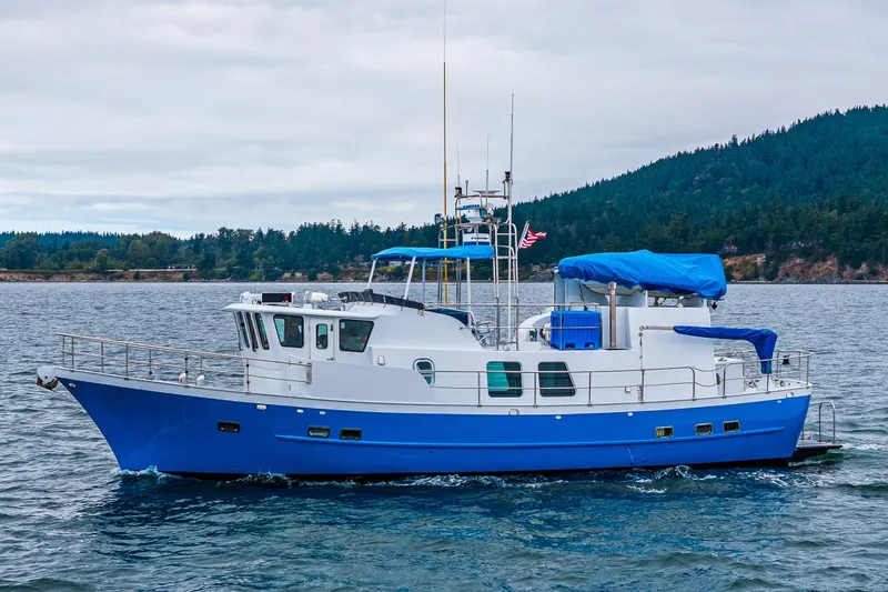 Slide: The Image of 1978 Hidden Harbor Custom Trawler cruising on scenic waters with forested hills in the background. - 9