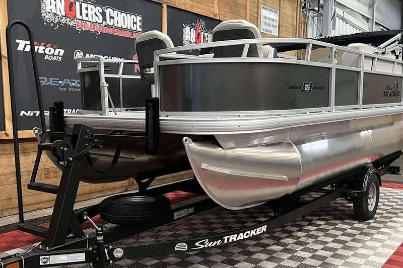 Slide: The Image of 2026 Sun Tracker Bass Buggy® 16 XL Select pontoon boat on trailer in showroom. - 8