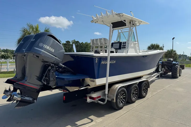 Slide: The Image of 2000 Regulator 26 Center Console boat on trailer with Yamaha engines, parked outdoors. - 2