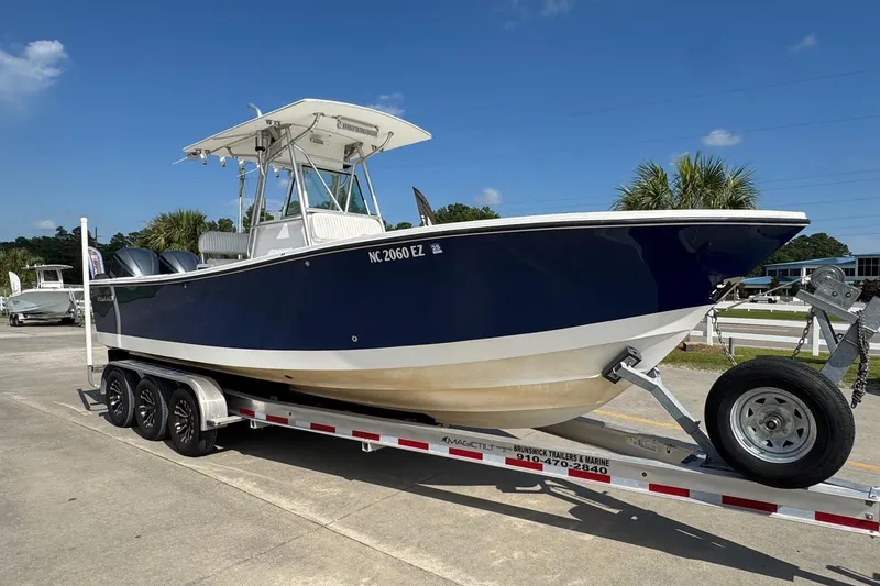 Slide: The Image of 2000 Regulator 26 Center Console boat on trailer, parked outdoors under clear blue sky. - 5