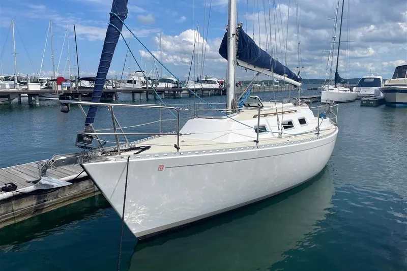 Slide: The Image of 1986 J Boats J/28 sailboat docked in a marina under a partly cloudy sky. - 1