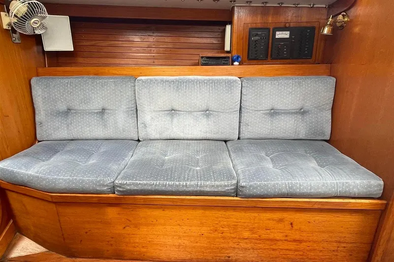 Slide: The Image of 1986 J Boats J/28 interior with blue cushioned seating and wooden paneling. - 31