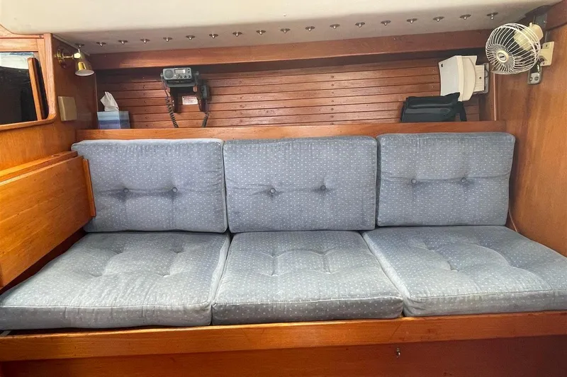 Slide: The Image of Interior of 1986 J Boats J/28 with blue cushioned seating and wooden paneling. - 32