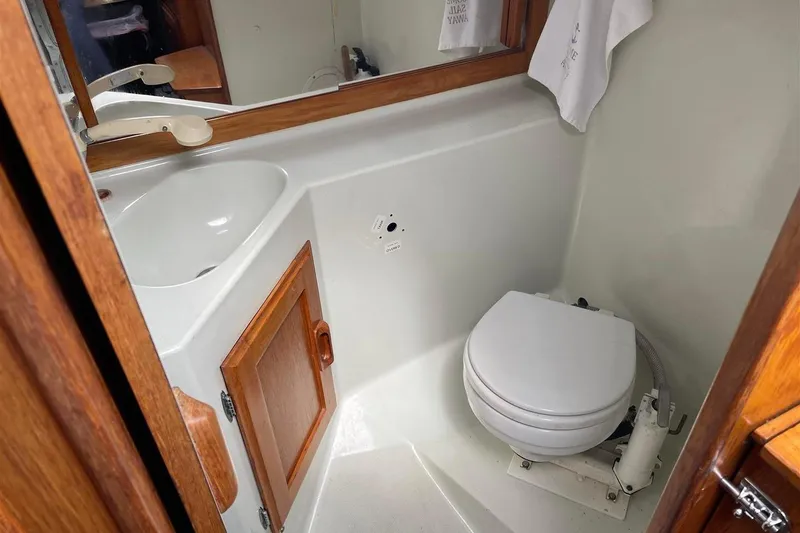 Slide: The Image of 1986 J Boats J/28 yacht bathroom with sink, toilet, and wooden cabinetry. - 33