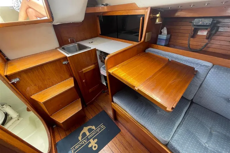 Slide: The Image of 1986 J Boats J/28 interior with wooden cabinetry, foldable table, and cozy seating area. - 34
