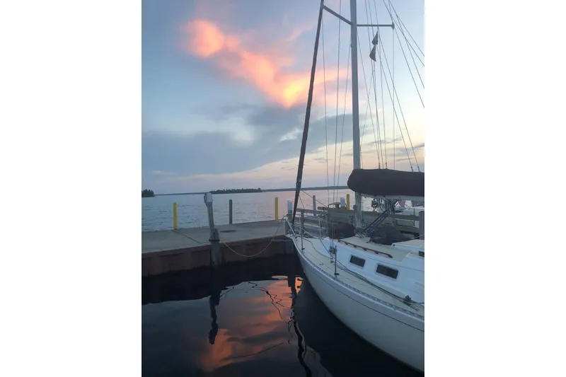 Slide: The Image of 1986 J Boats J/28 sailboat docked at sunset with colorful sky reflections. - 42