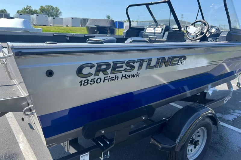 Slide: The Image of 2024 Crestliner 1850 Fish Hawk boat on trailer, showcasing sleek design and branding. - 1