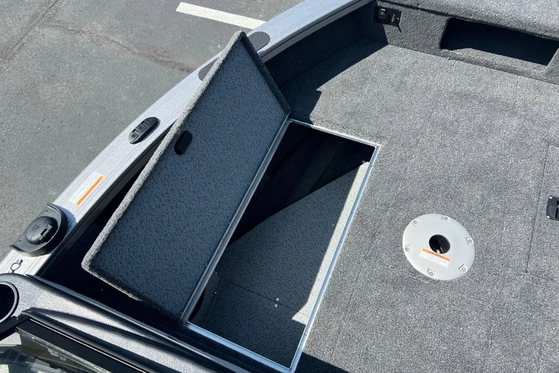 Slide: The Image of 2024 Crestliner 1850 Fish Hawk boat interior with open storage compartment and carpeted deck. - 4