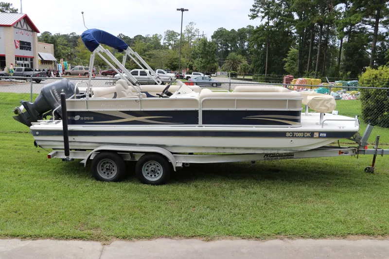 Slide: The Image of 2014 Hurricane FunDeck 226 boat on trailer, parked on grass near a store. - 0