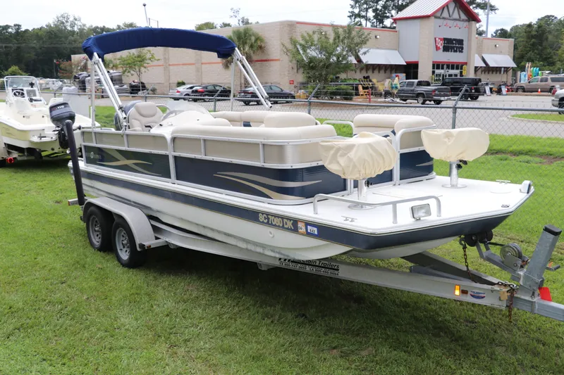 Slide: The Image of 2014 Hurricane FunDeck 226 boat on trailer, parked on grass near a store. - 2