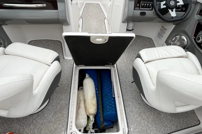 Slide: The Image of 2013 Chaparral 226 SSi boat interior with open storage compartment and white seats. - 14