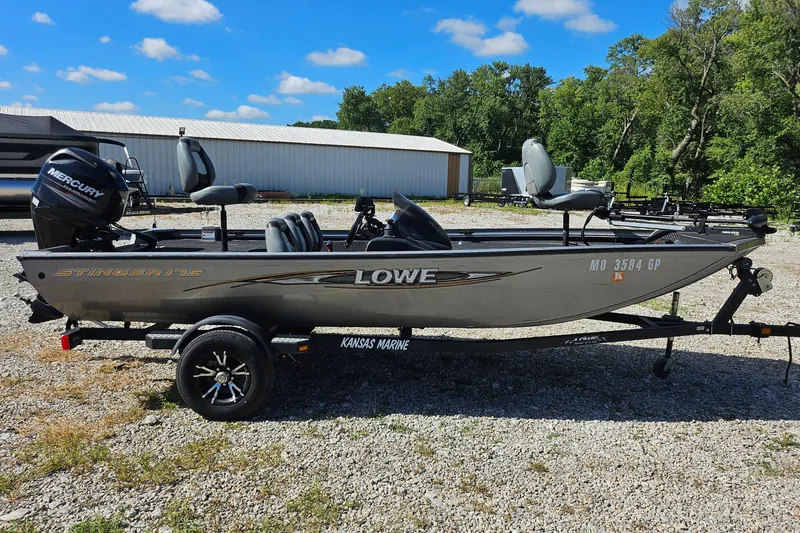 Slide: The Image of 2015 Lowe Stinger 175 fishing boat on trailer, parked outdoors under blue sky. - 1