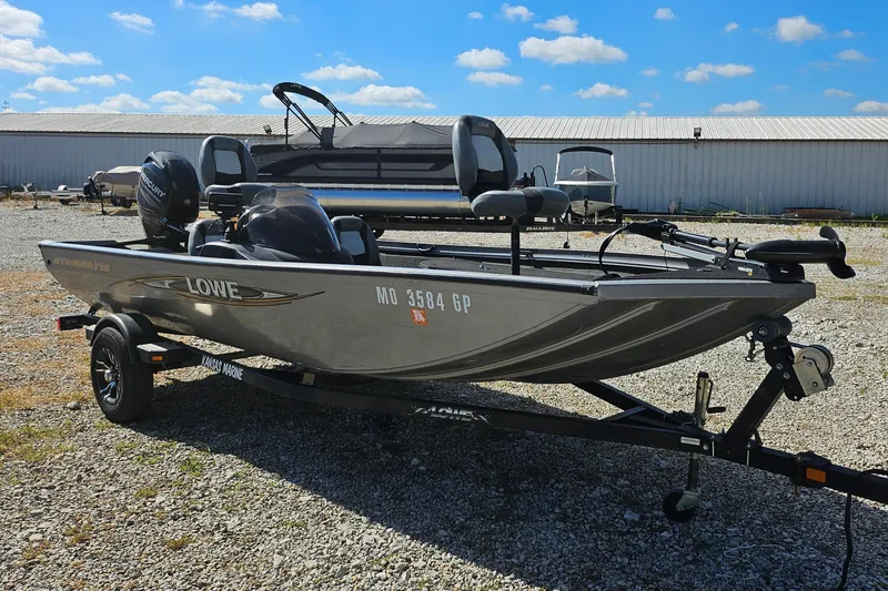 Slide: The Image of 2015 Lowe Stinger 175 boat on trailer, parked outdoors under blue sky. - 2