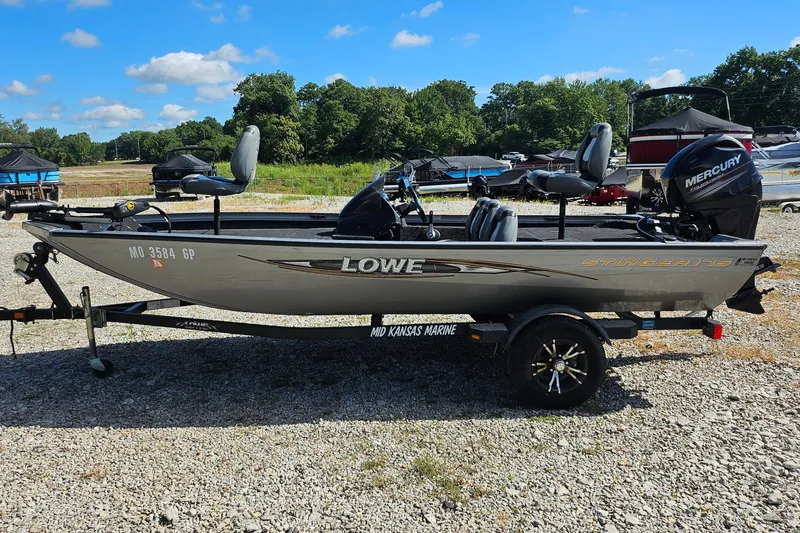 Slide: The Image of 2015 Lowe Stinger 175 boat on trailer, parked outdoors under a clear blue sky. - 5