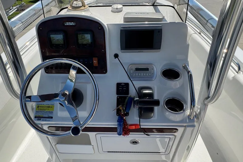 Slide: The Image of 2012 Sea Hunt Triton 225 boat console with steering wheel, gauges, and cup holders. - 13