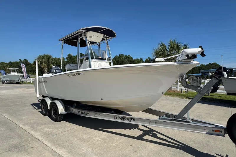 Slide: The Image of 2012 Sea Hunt Triton 225 boat on trailer, parked outdoors under clear blue sky. - 5