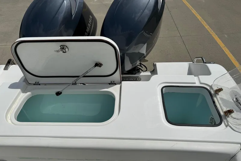 Slide: The Image of 2014 Sea Hunt Gamefish 25 boat with open storage compartments and dual Yamaha engines. - 20
