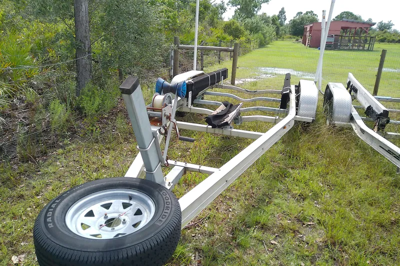 Slide: The Image of Boat trailer for 2008 Everglades 210CC, parked on grassy area near fence. - 49