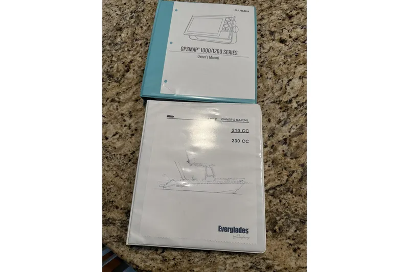 Slide: The Image of Manuals for Garmin GPSMAP and 2008 Everglades 210 Center Console on granite surface. - 59